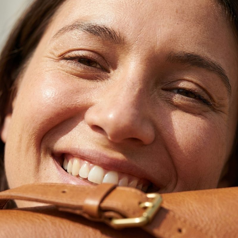 An extreme close-up of a smiling face, with only a little of the strap showing